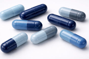 Blue and light blue methylene blue capsules in varying shades arranged on a clean white background, illustrating differences in capsule color and appearance.
