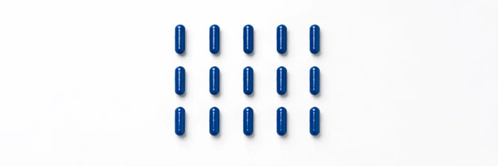 Blue methylene blue capsules arranged in a clean grid on a white background representing precise dosing