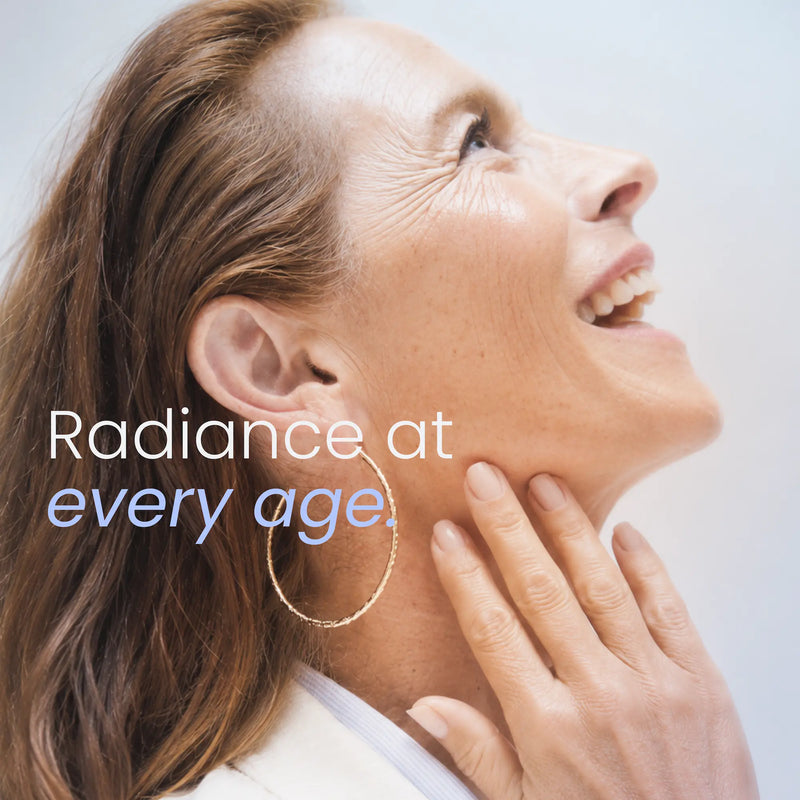 A close-up lifestyle shot of a smiling woman looking upward, touching her jawline, wearing a gold hoop earring and a white collared shirt. The text 'Radiance at every age.